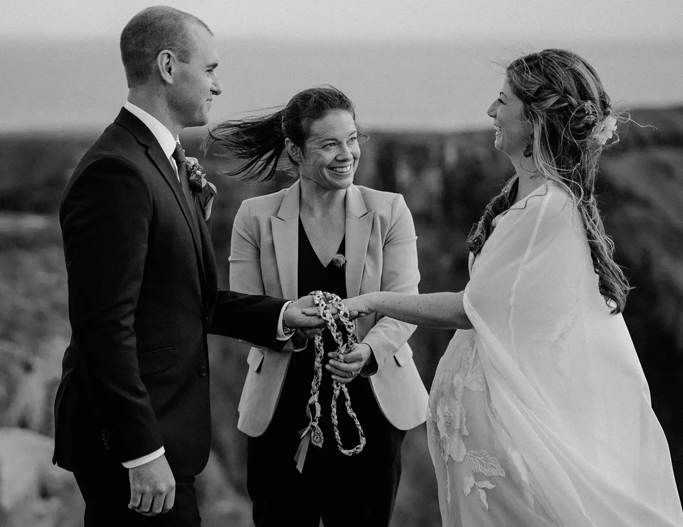 Irish destination wedding ceremony in Ireland — bride and groom standing with their celebrant during a handfasting ritual at their wedding ceremony.
