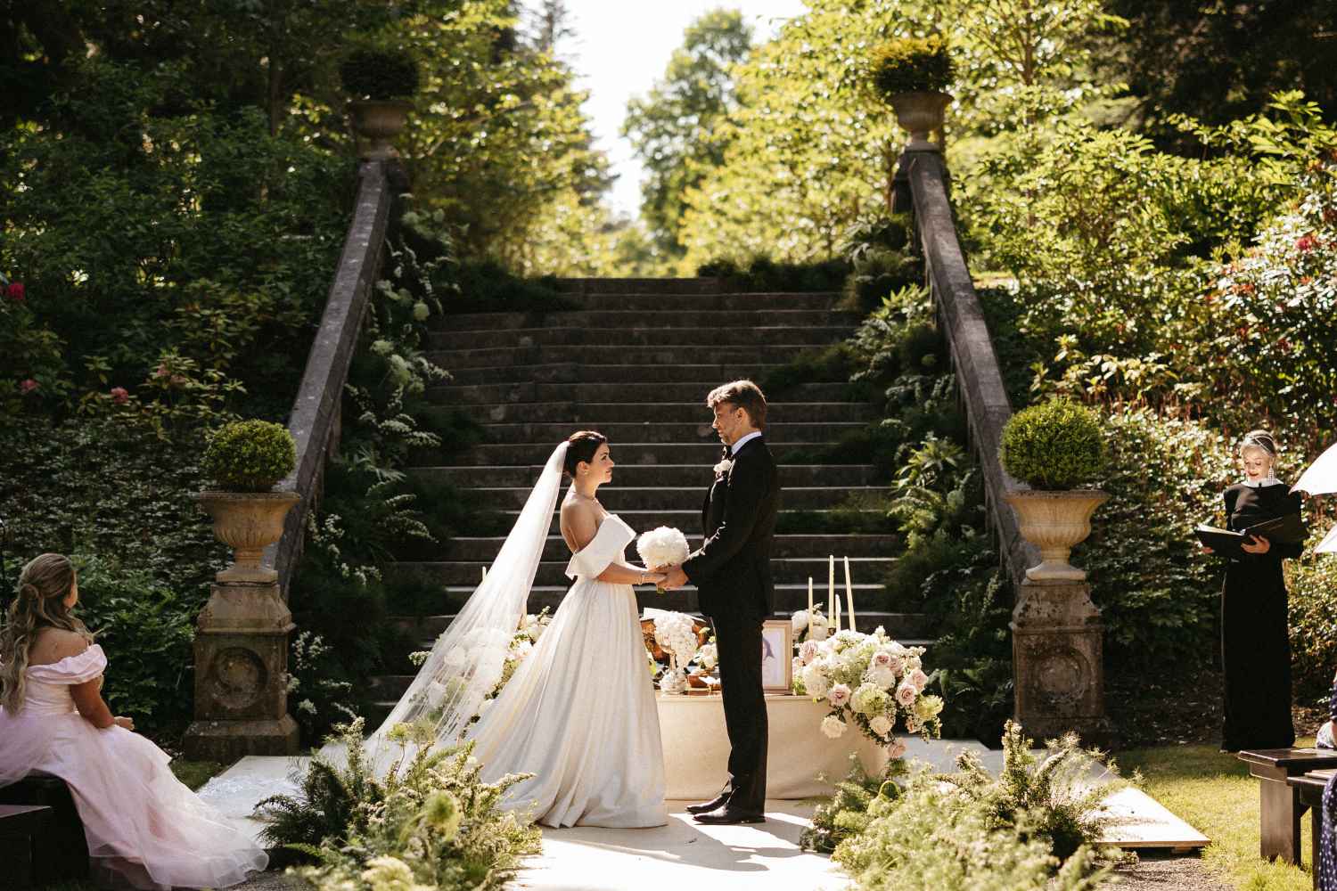 Couple exchanging wedding vows during an outdoor ceremony at Ashford Castle in Ireland surrounded by guests.