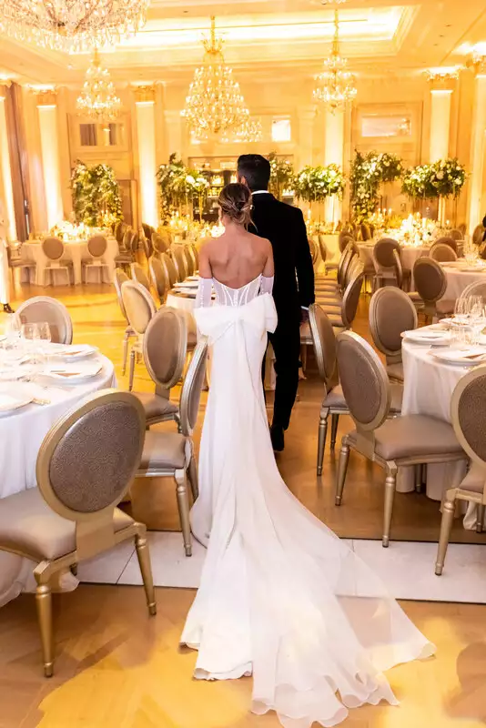 Destination wedding at Adare Manor, County Limerick — bride and groom during their wedding dinner reveal in the ballroom, with the bride wearing a gown featuring a bow at the back and a flowing train.