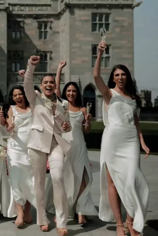 Destination wedding in Ireland at Adare Manor, County Limerick — bridal party outdoors on the estate celebrating and cheering in white bridesmaids dresses.