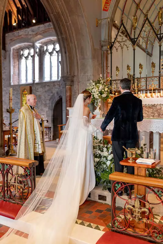 Destination wedding ceremony at Adare Manor, County Limerick — bride and groom at the altar during a church ceremony, with the bride wearing a flowing veil.