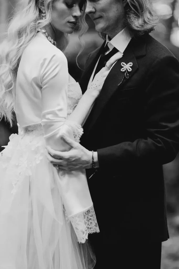 Black-and-white close-up of a bride and groom embracing, heads touching, hands holding each other.
