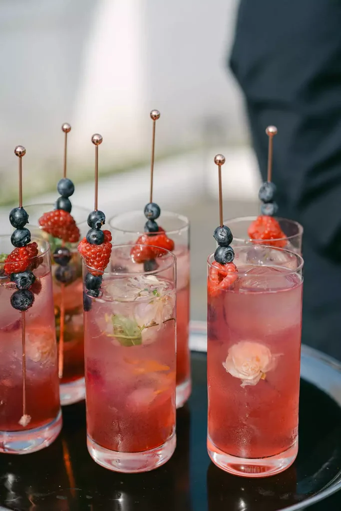 Destination wedding at Ashford Castle, County Mayo — red cocktails served on a tray with metal skewers and blueberry and raspberry garnishes during a reception drinks service.