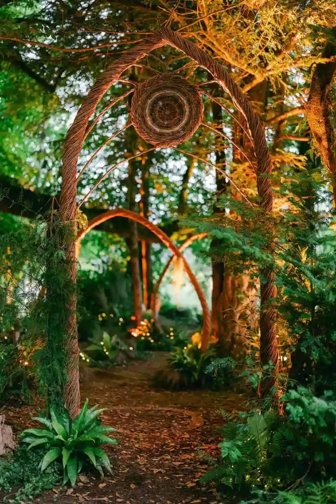 Destination wedding at Ashford Castle, County Mayo — custom willow arch surrounded by greenery within a forest setting for an outdoor ceremony installation.