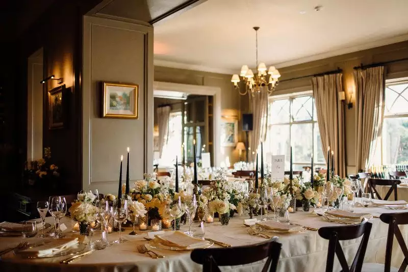 Destination wedding dinner at Ballynahinch Castle, County Galway, Ireland — candlelit table setting with floral arrangements at the centre and bespoke place cards designed as part of the wedding stationery suite.