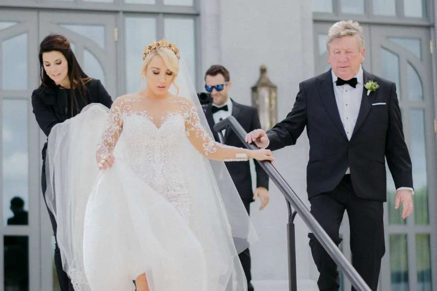 Destination wedding in Ireland — Olivia Buckley assisting a bride with her gown train as she descends a staircase during a wedding celebration.