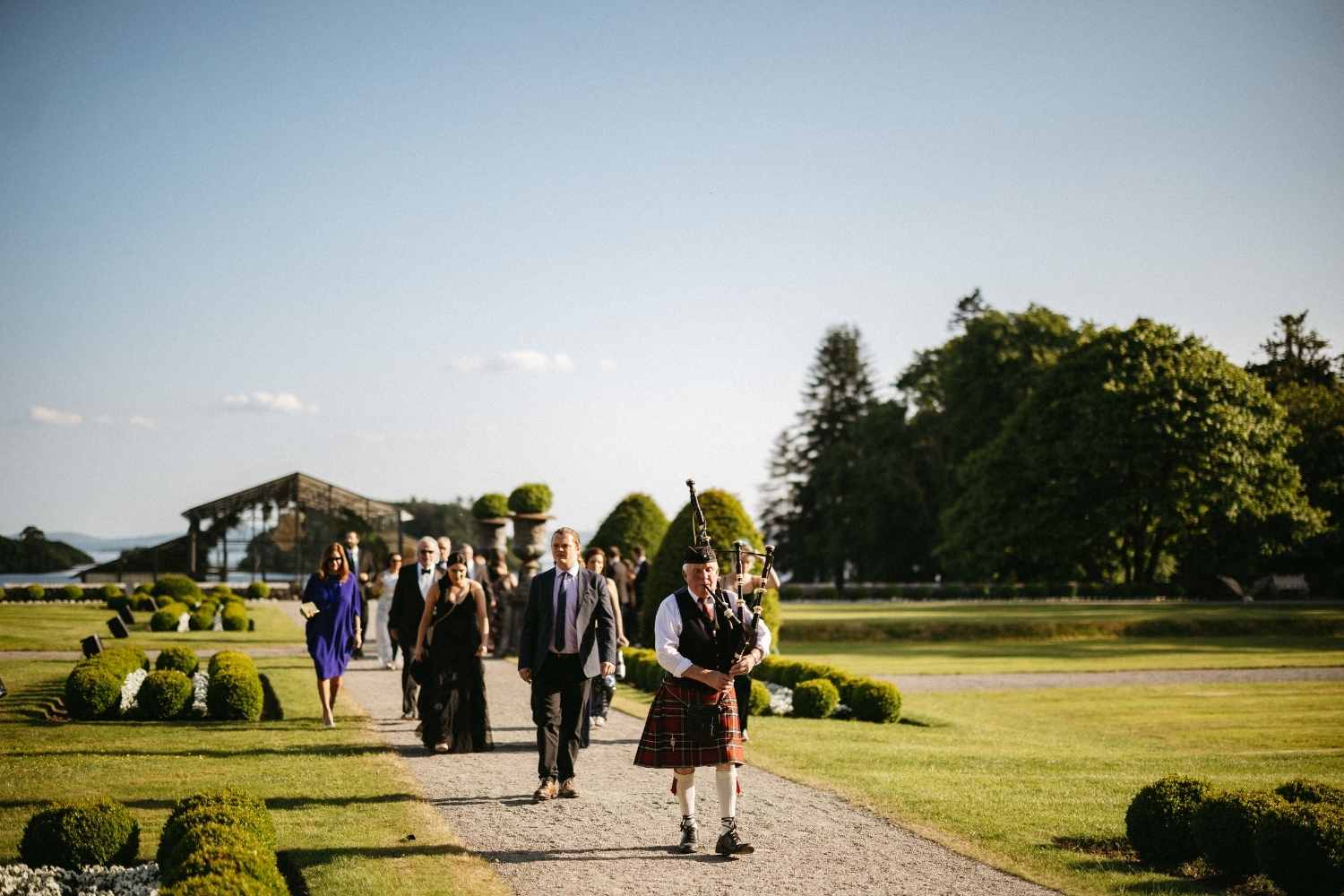 Traditional Irish piper leading wedding guests to dinner at Ashford Castle during a luxury destination wedding in Ireland.