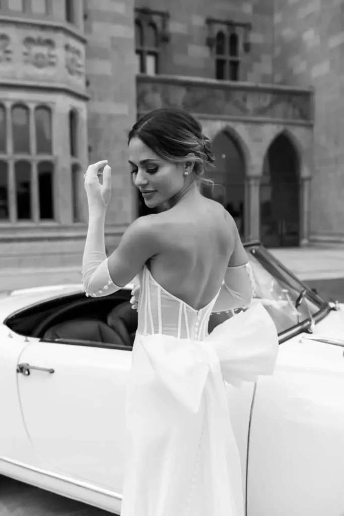 Irish destination wedding at Adare Manor, County Limerick — bride in her gown outdoors on the estate, featuring a large bow at the back of the dress and wearing gloves.
