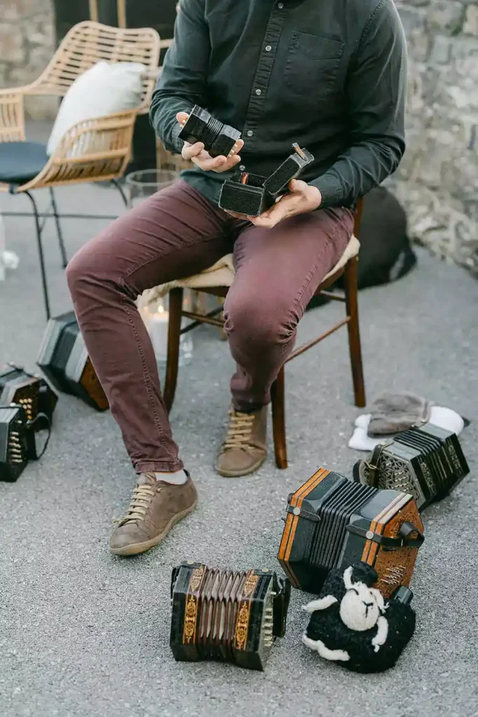 Irish destination wedding at Ashford Castle, County Mayo — musician seated with a collection of concertinas, holding one instrument while preparing for live entertainment.