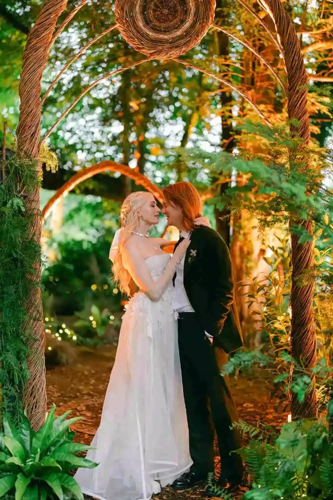 Irish destination wedding at Ashford Castle, County Mayo — bride and groom embracing beneath a bespoke willow archway within a wooded setting, looking towards one another during a portrait session.