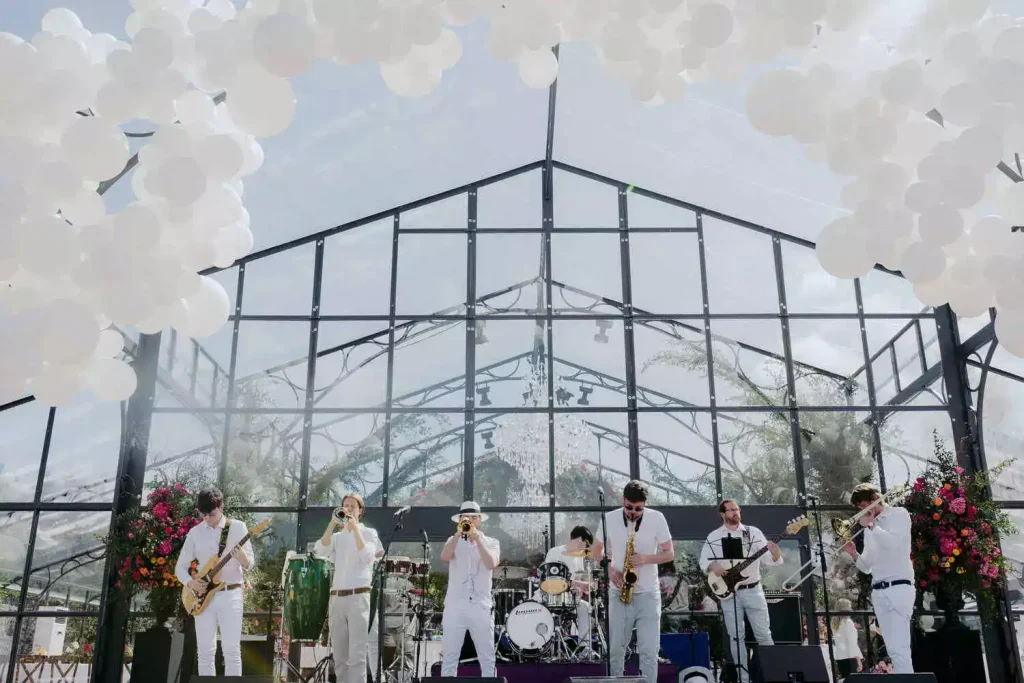 Private celebration in Ireland — live entertainment from a band performing on stage in front of a glass marquee with a large balloon arch.