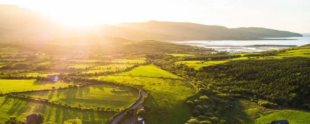 Destination wedding in Ireland — aerial landscape of the Irish coastline with rolling green fields, bay views, and mountain scenery.