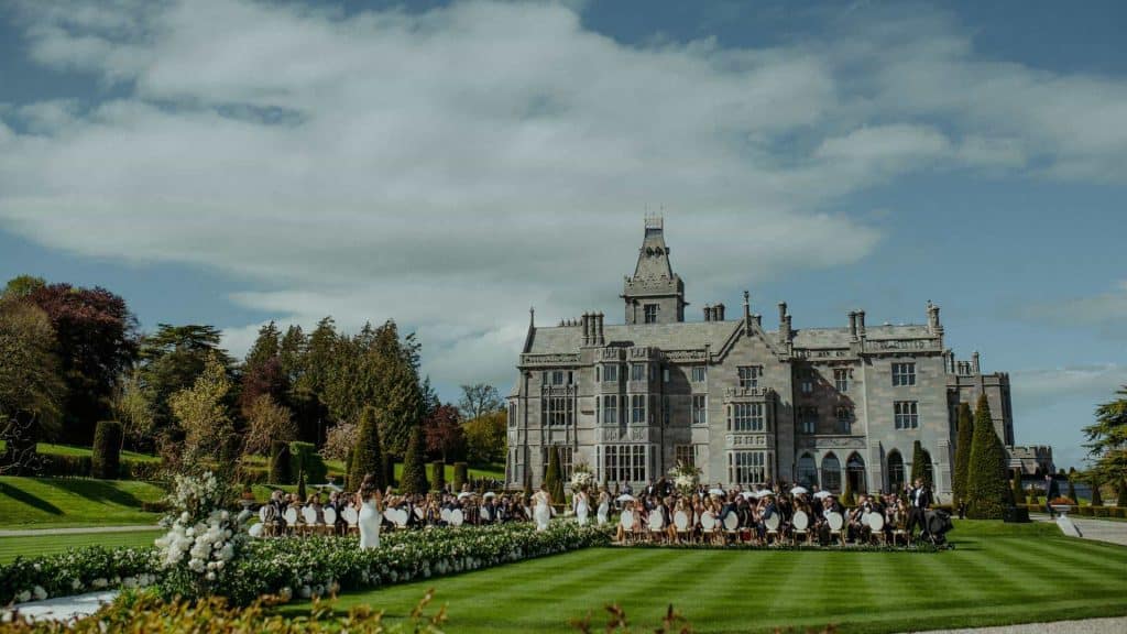Destination wedding ceremony at Adare Manor, County Limerick — bridesmaids processing up the aisle before the outdoor ceremony on the estate grounds.