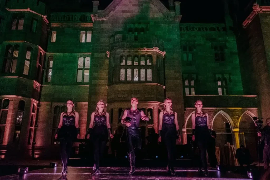 Destination wedding in Ireland at Adare Manor, County Limerick — five Irish dancers performing outdoors at night with the manor illuminated in the background.