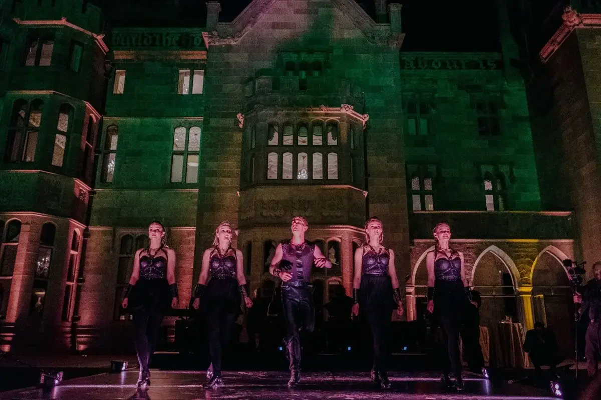 Destination wedding in Ireland at Adare Manor, County Limerick — five Irish dancers performing outdoors at night with the manor illuminated in the background.