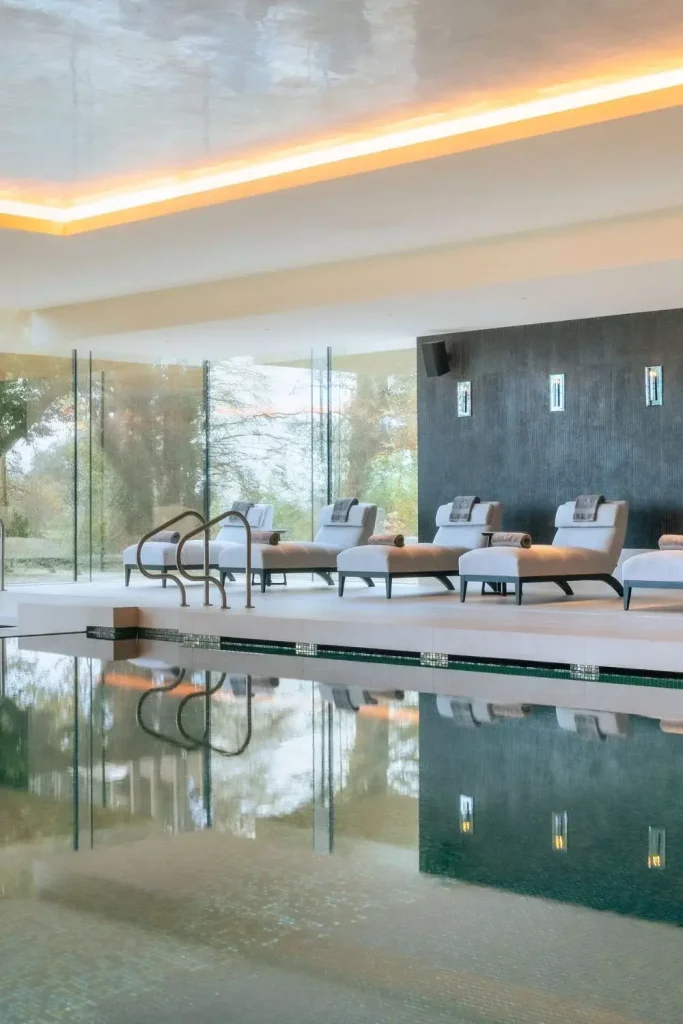 Irish castle wedding at Adare Manor, County Limerick — serene swimming pool area with clear water, neatly arranged lounge chairs with towels at the poolside, and a calm, light-filled spa setting within the estate grounds.