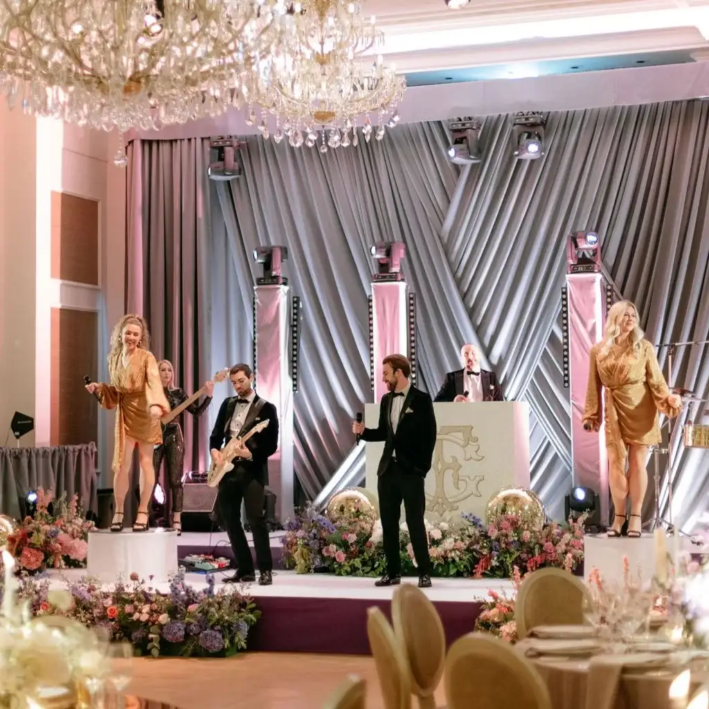 Destination wedding at Adare Manor, County Limerick — live party band performing on stage during a late-night reception, with instruments, microphones, and dynamic stage lighting creating an energetic performance atmosphere within the ballroom setting.