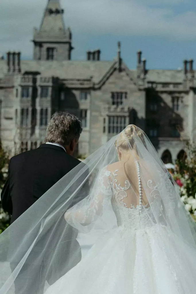 Destination wedding ceremony at Adare Manor, County Limerick — bride walking up the aisle with her father on the estate grounds.