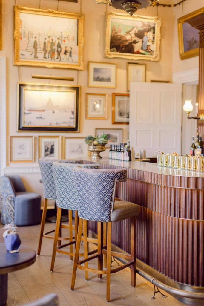 Irish destination wedding at Cashel Palace, County Tipperary — elegant cocktail bar with three patterned high stools and framed paintings on the wall creating a refined interior reception setting.