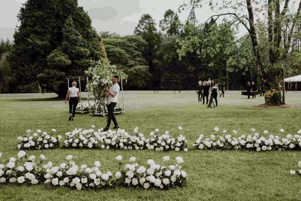 Ireland destination wedding ceremony at Lough Eske, County Donegal — outdoor floral aisle installation and ceremony styling on the castle grounds, with floral arrangements being prepared and placed ahead of the ceremony.