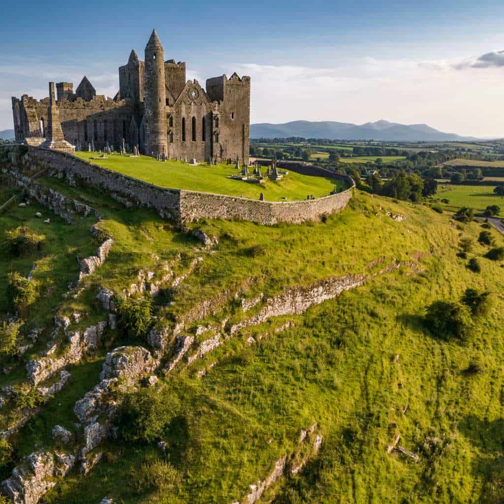 Irish destination wedding in Ireland at the Rock of Cashel, County Tipperary — dramatic heritage landmark rising above the landscape, viewed against open skies and surrounding greenery.
