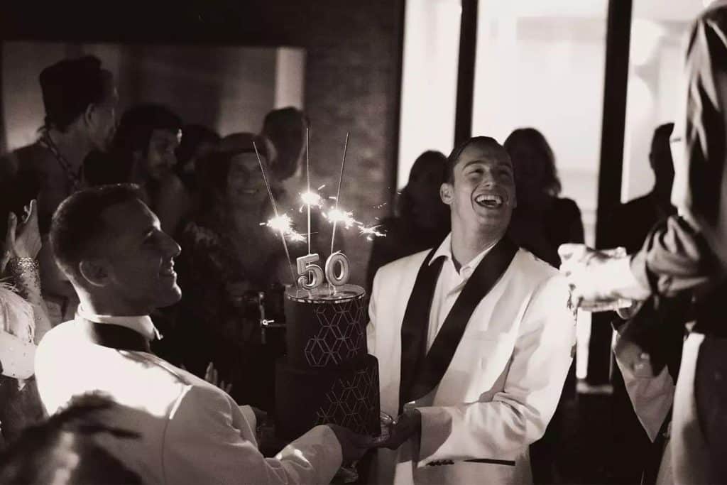 Private party planner Ireland at a private house in Dublin, where performers present a 50th birthday cake as a theatrical moment within a high-energy milestone celebration.