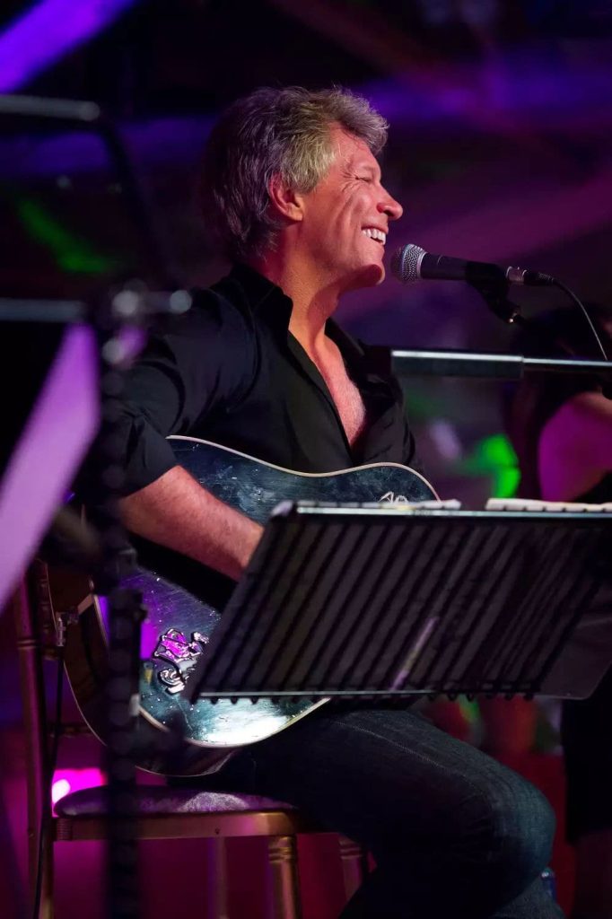 Private party planner Ireland at Luttrellstown Castle, County Dublin — live musical performance featuring a smiling singer with guitar under atmospheric lighting, set within an elegant private celebration atmosphere.