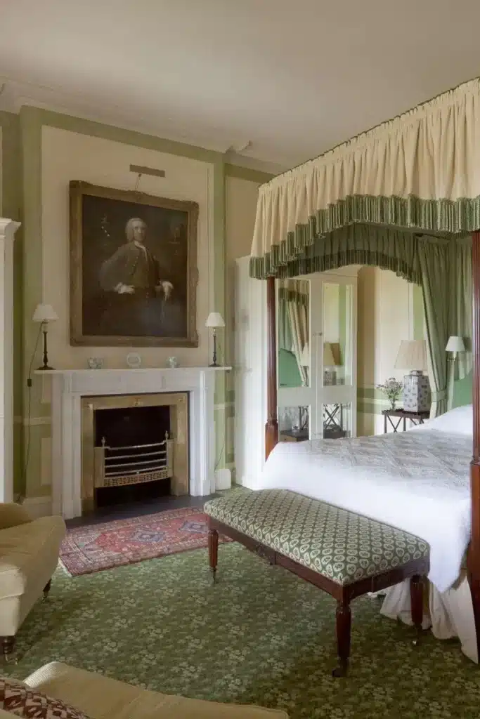 Irish destination wedding Ballyfin Demesne, County Laois, Ireland — Knights Room stateroom with a green-themed interior, featuring a four-poster bed and a Regency chimneypiece in white marble within a grand historic bedroom setting.