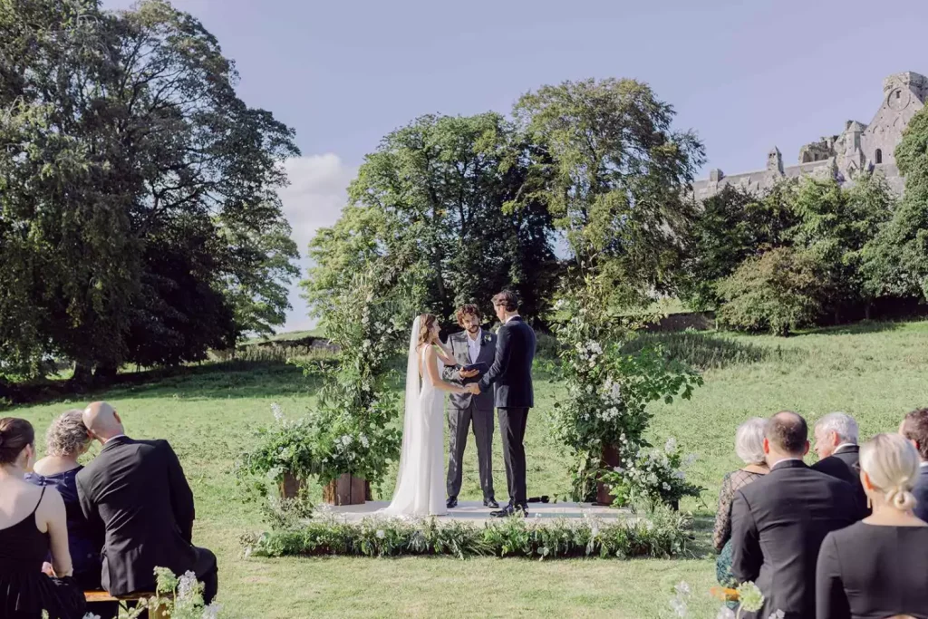 Irish destination wedding at Cashel Palace, County Tipperary — wedding ceremony at the foothills of the Rock of Cashel during an outdoor celebration.