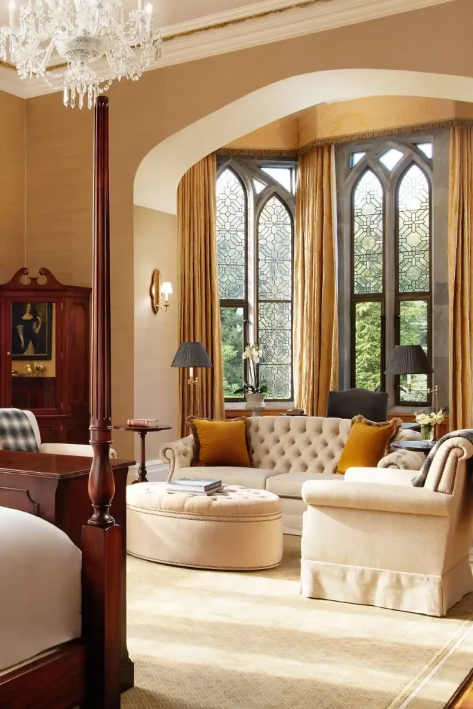 Irish castle wedding at Adare Manor, County Limerick — The Dunraven Suite interior featuring a balance of light and dark furnishings, elegant seating, and ornate window panelling that frames bright natural light within the castle suite.