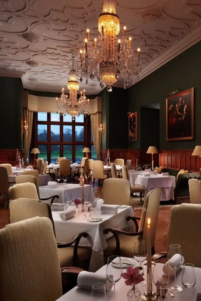 Irish castle wedding at Adare Manor — Oak Room dining interiors with chandelier lighting, candlelit dining tables, and framed paintings within the manor house.