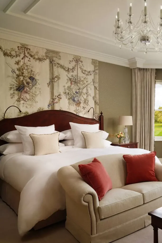 Irish castle wedding at Adare Manor, County Limerick — Stateroom interior featuring a grand bed with plush bedding, a sofa placed at the foot of the bed, and richly patterned wallpaper within an elegant castle suite setting.