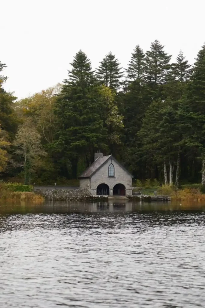 Irish castle wedding at Ashford Castle — Boathouse with a small stone exterior perched on the edge of Lough Corrib, surrounded by tall mature trees and lakeside setting.