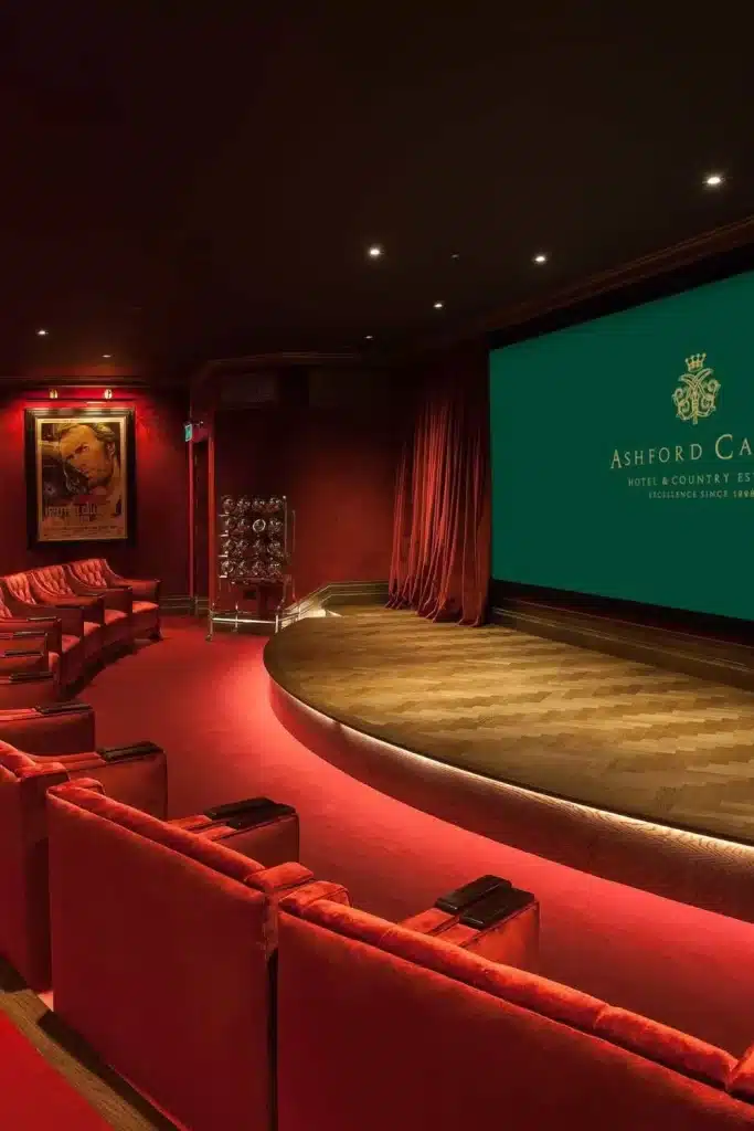 Irish castle wedding at Ashford Castle — private cinema room with red lounge seating, large screen entertainment area, and soft lighting within the castle interior.