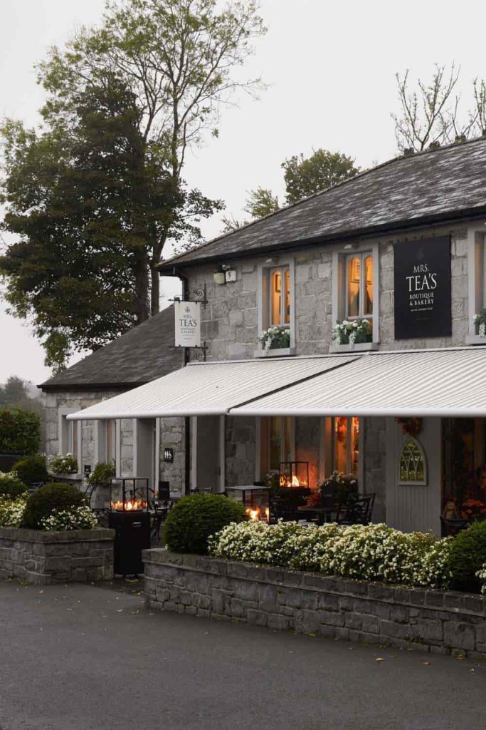 Irish castle wedding at Ashford Castle — Mrs Tea’s Boutique & Bakery with a charming stone exterior, covered terrace seating, and outdoor fire heaters on the estate grounds.