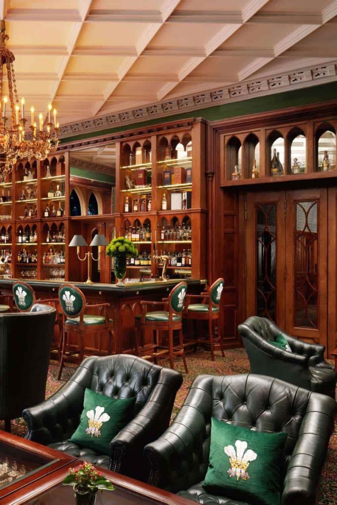 Irish castle wedding at Ashford Castle — Prince of Wales Bar with green upholstered lounge seating, emblem bar stools, and a stocked cocktail bar interior.