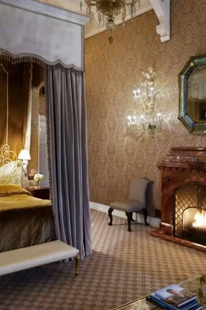 Irish castle wedding at Ashford Castle — Stateroom with high ceilings, feature bed, antique furnishings, original fireplace, and views toward Lough Corrib within the historic castle interior.