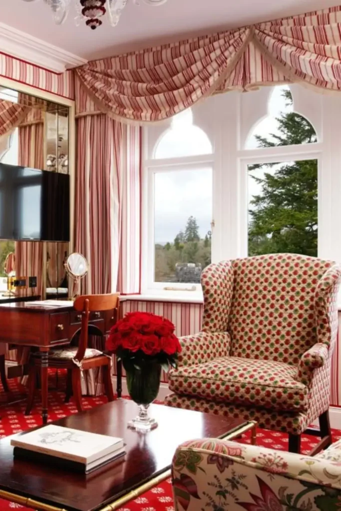 Irish castle wedding at Ashford Castle — suite interior with red carpet flooring, patterned armchairs, red striped curtains, and a wooden table and chair in the corner.