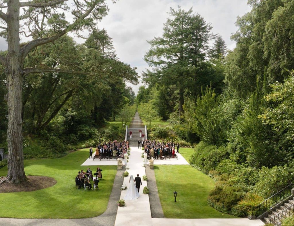 Castle wedding in Ireland at Ashford Castle, County Mayo — aerial view of a wedding ceremony at the Long Steps on the castle grounds.