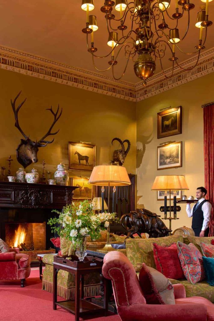 Destination wedding at Dromoland Castle, County Clare — The Gallery lounge with guest seating, a lit fireplace, and a mounted deer head above the mantel.