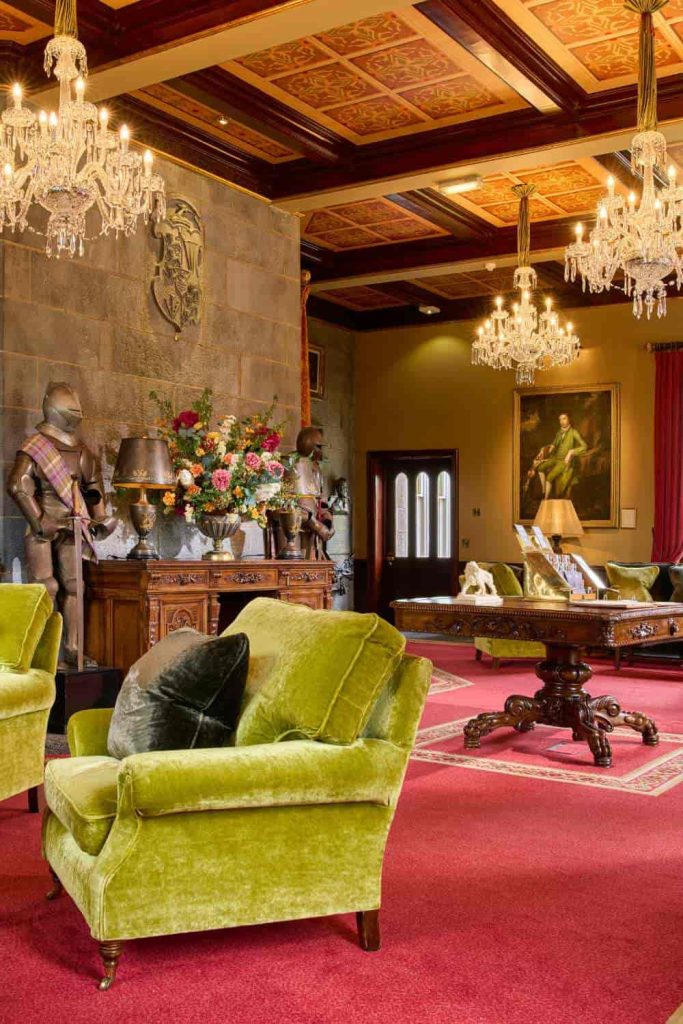 Destination wedding at Dromoland Castle, County Clare — lobby interior with green upholstered armchairs, chandeliers, and suits of armour displayed throughout the space.