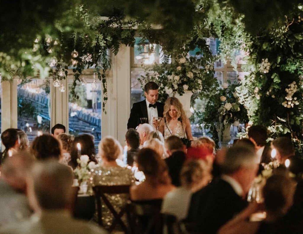 Destination wedding guest experience at Lough Eske Castle — immersive indoor garden reception with guests seated for dinner beneath suspended florals.