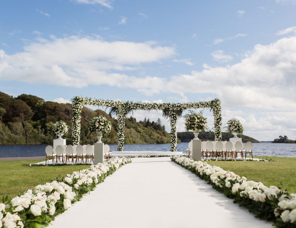 Intimate destination wedding at Ashford Castle, County Mayo — rose floral arch overlooking Lough Corrib during a private ceremony on the estate.