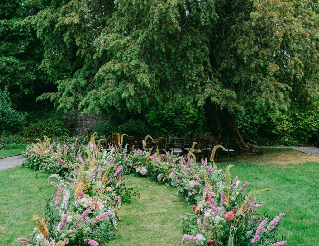 Intimate destination wedding at Ashford Castle, County Mayo — wedding ceremony in the walled garden surrounded by seasonal pink florals.