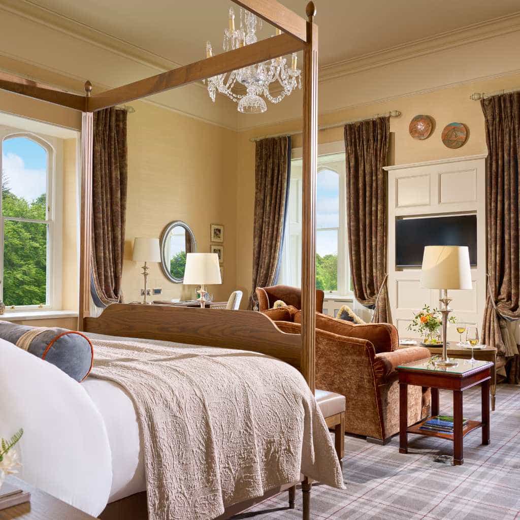 Irish castle wedding at Dromoland Castle, County Clare — Viscount Stateroom with a four-poster bed and a separate lounge seating area within the suite.