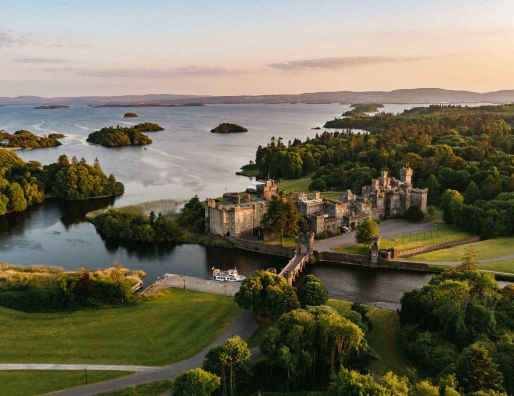 Irish castle wedding at Ashford Castle, County Mayo — aerial view of the castle estate overlooking Lough Corrib and the surrounding grounds.
