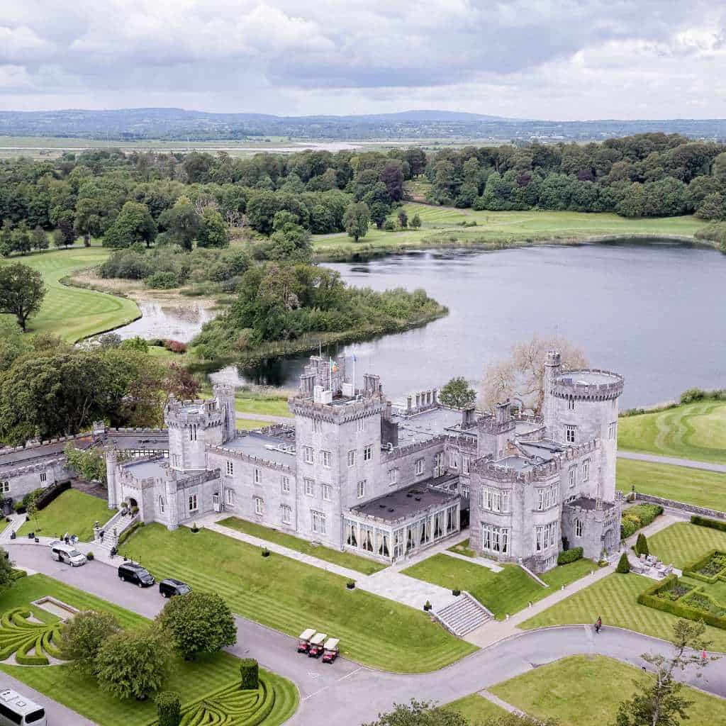 Irish castle wedding at Dromoland Castle, County Clare — aerial view of the estate showing the castle, manicured lawns, surrounding lake, and dense forestry.