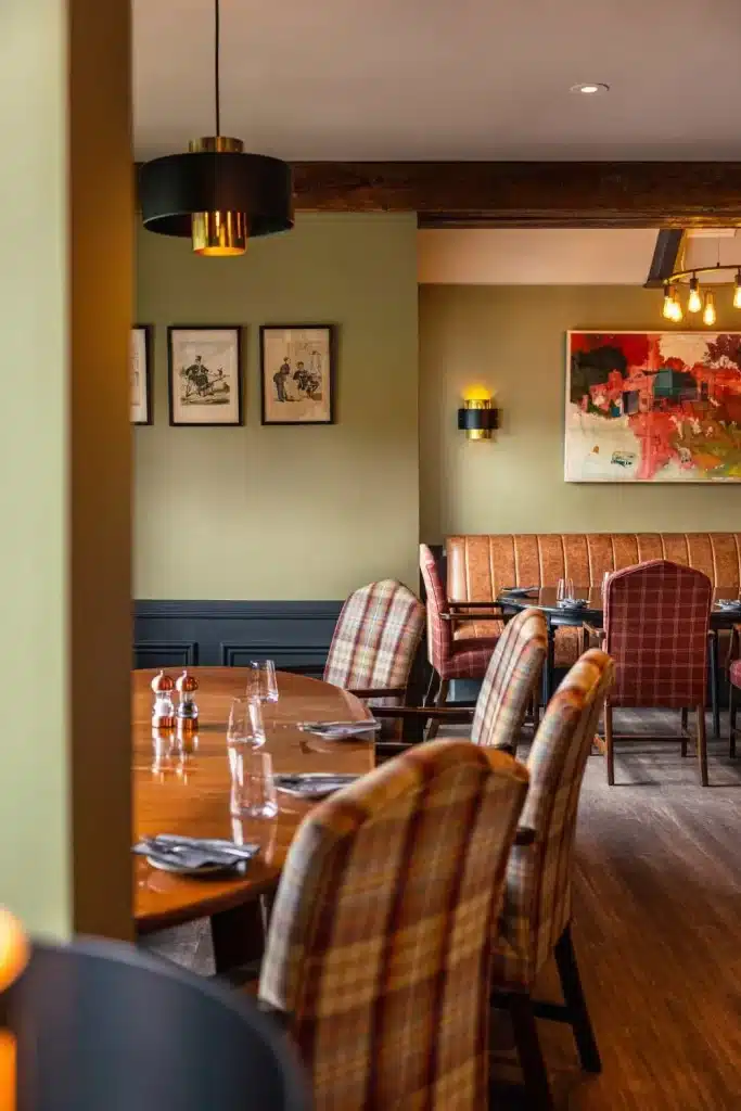 Irish destination wedding at Dromoland Castle, County Clare — Fig Tree Restaurant dining room with checkered upholstered chairs, tables set for dinner service, and sage green walls featuring framed artwork.