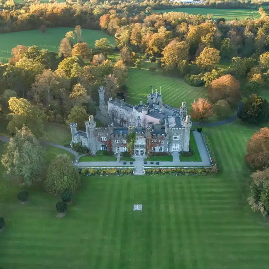 Historic castle venue at Luttrellstown Castle, County Dublin — aerial view of the castle surrounded by manicured lawns and mature trees across the estate grounds.