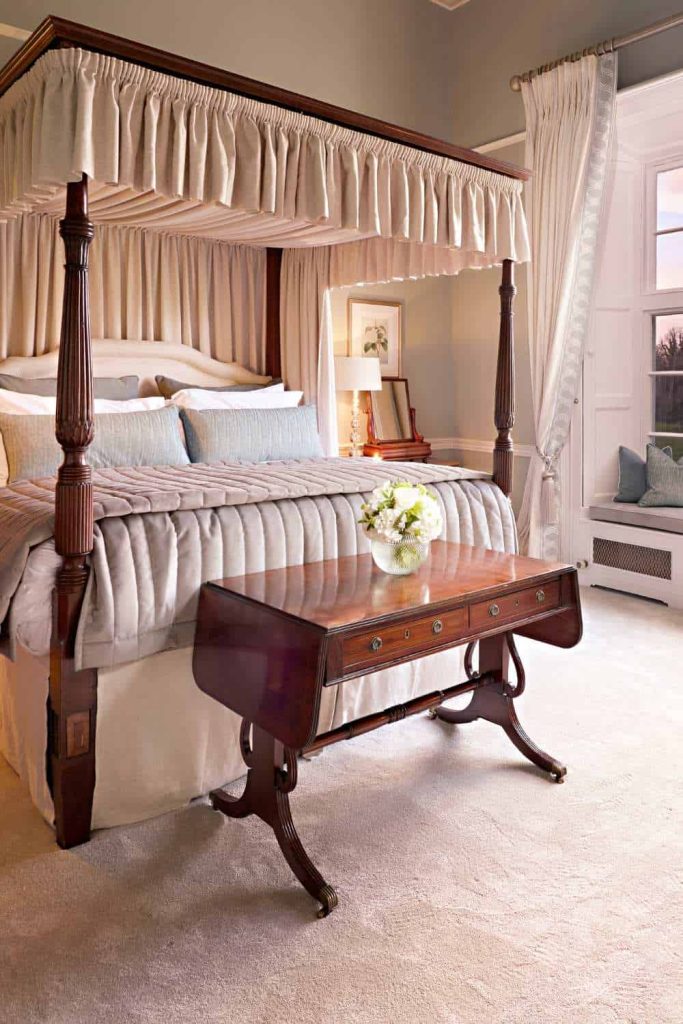 Luttrellstown Castle, County Dublin — The Luttrell Room with a four-poster bed, layered bedding and pillows, and a wooden table topped with a glass vase of flowers at the foot of the bed.